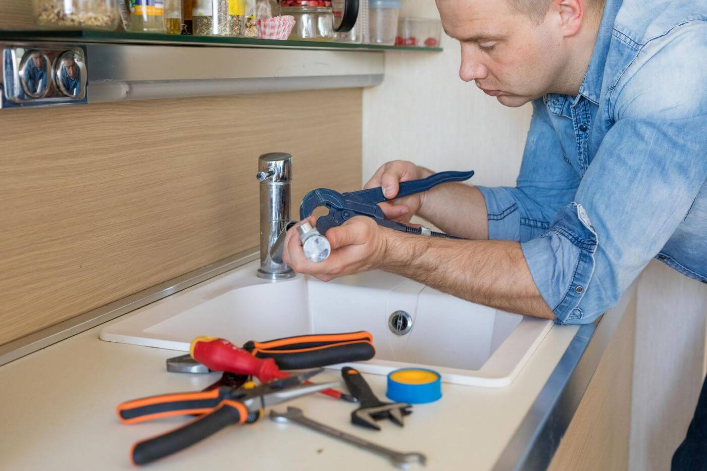 Man fixing leaking tap in kitchen