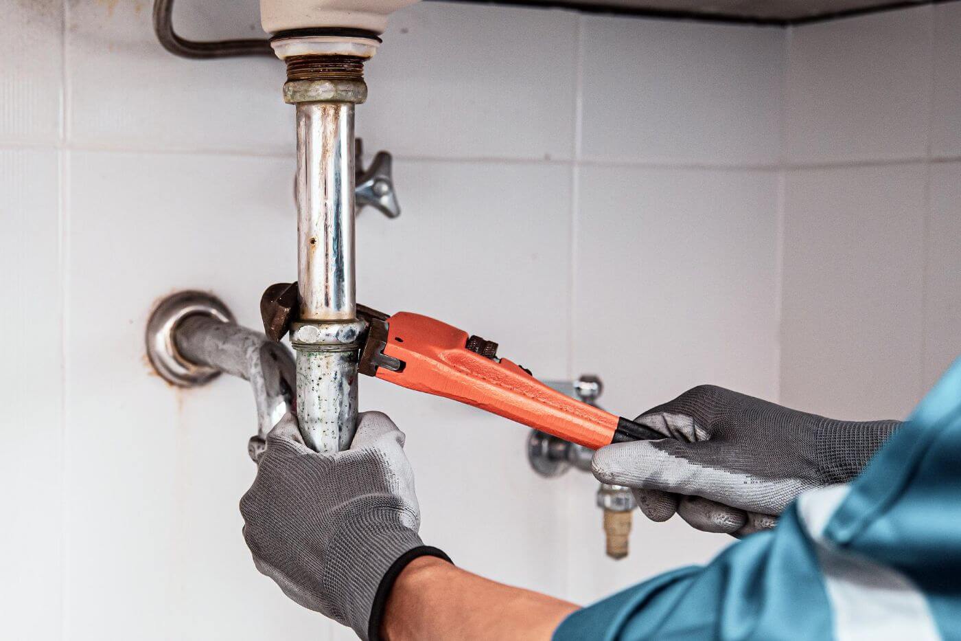 Plumber using a wrench to repair water pipe under the sink